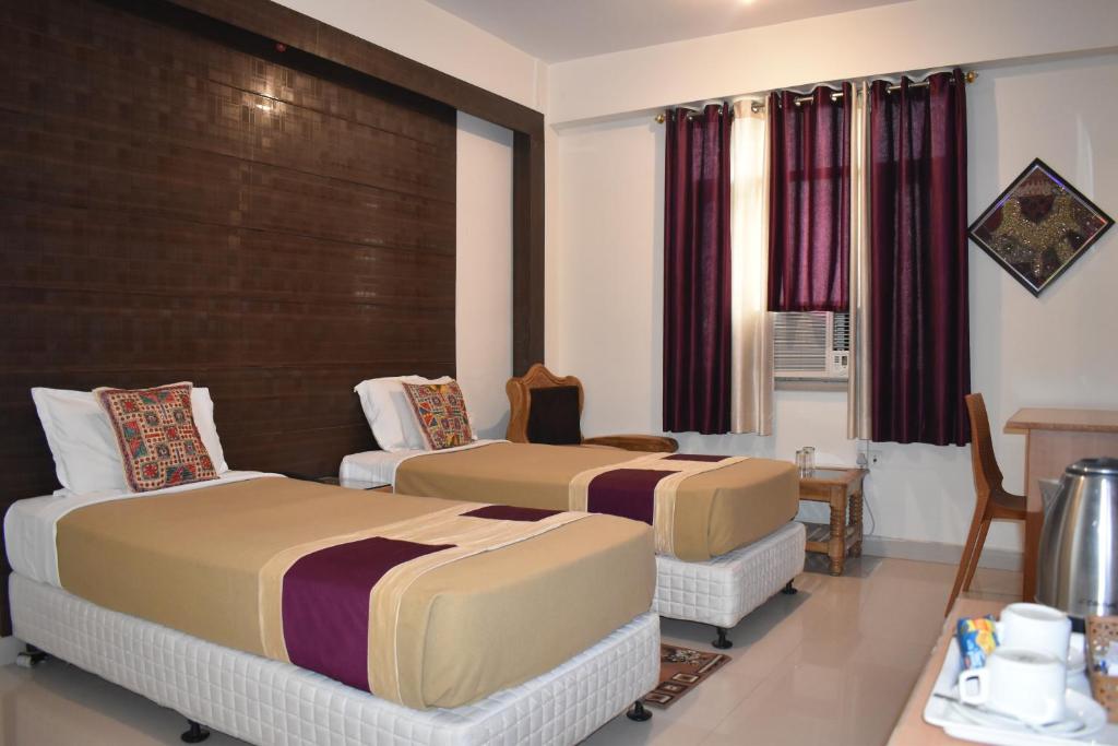 a hotel room with two beds and a table at Hotel Bodh Vilas in Bodh Gaya