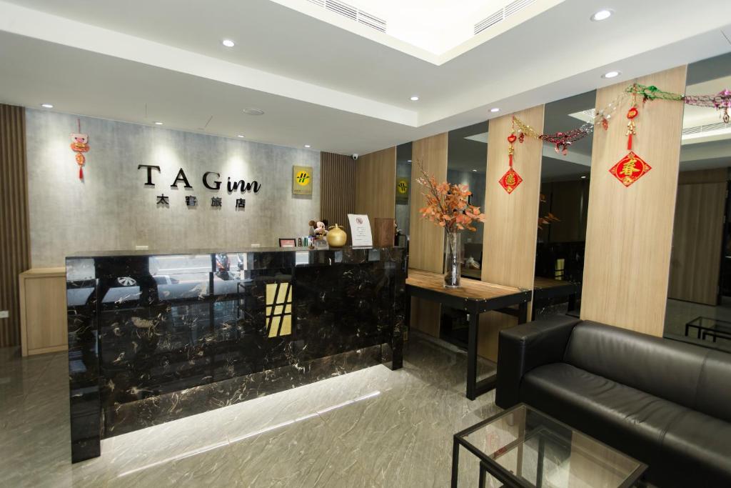 a lobby with a black couch and a counter at Tag inn in Taoyuan