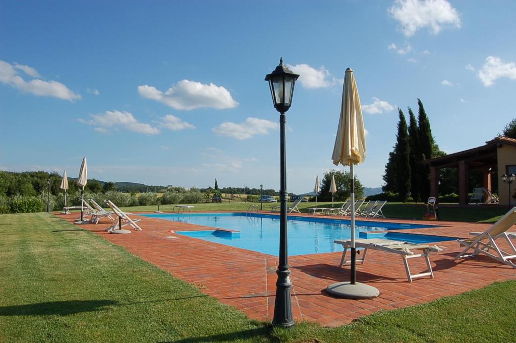 a pool with chairs and a light pole and an umbrella at Agriturismo Il Palazzo in Pergine Valdarno