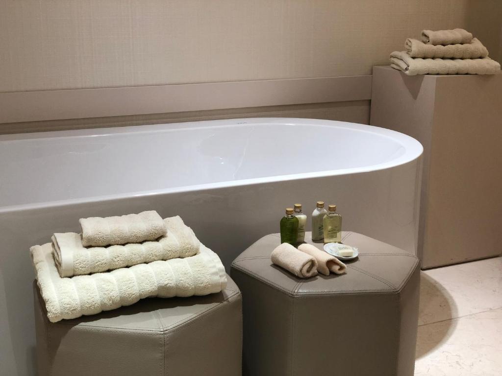a bathroom with a bath tub and two stools with towels at Kemer Country Hotel İstanbul in Istanbul