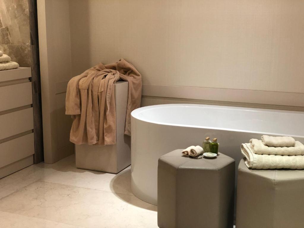a bathroom with a bath tub and two stools at Kemer Country Hotel İstanbul in Istanbul