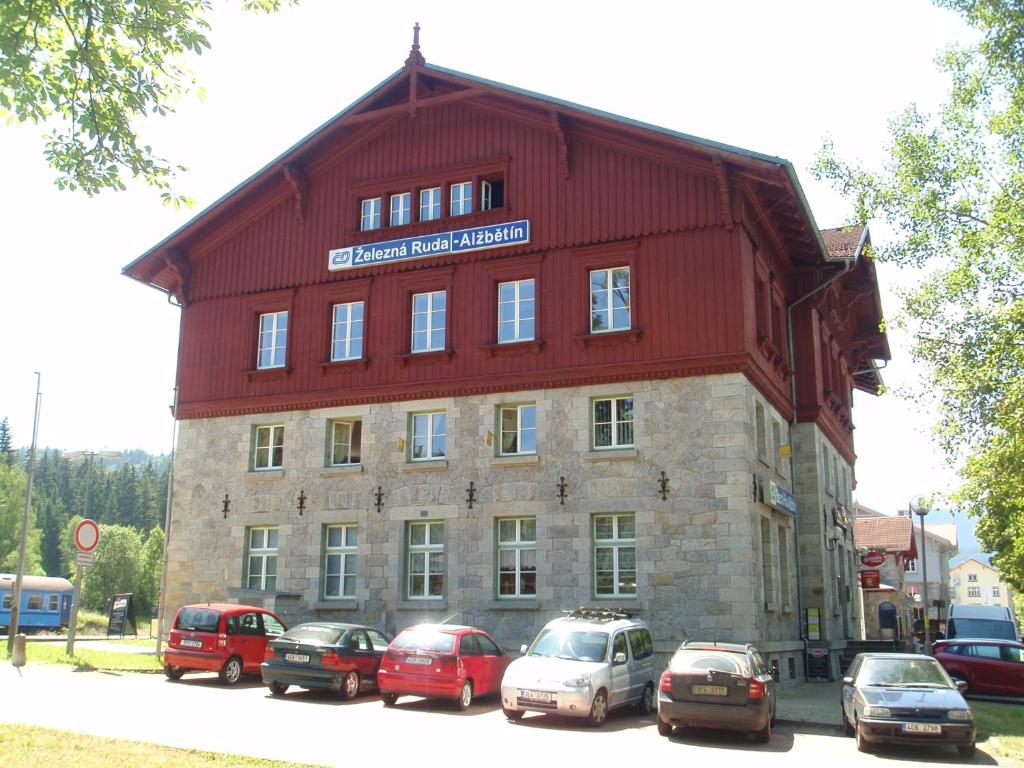 a large red building with cars parked in front of it at Apartmány Elisabeth in Železná Ruda