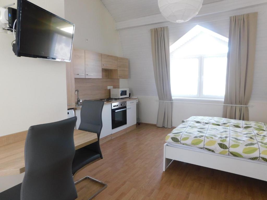 een slaapkamer met een bureau en een bed en een keuken bij Mona apartman in Keszthely