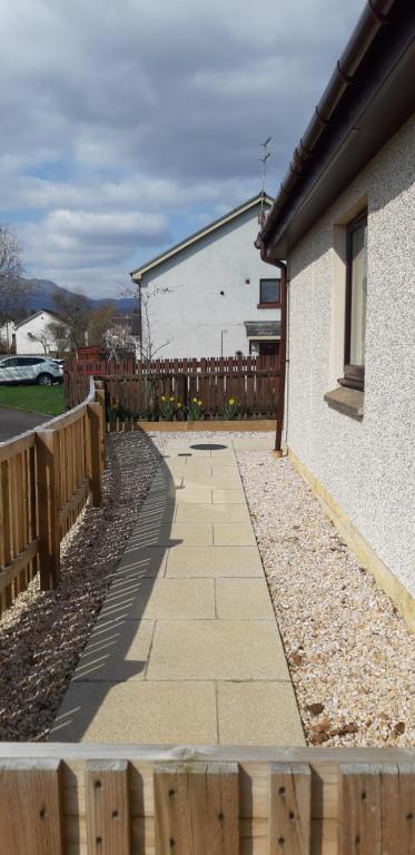 a sidewalk next to a house with a wooden fence at Ritchie selfcatering in Callander