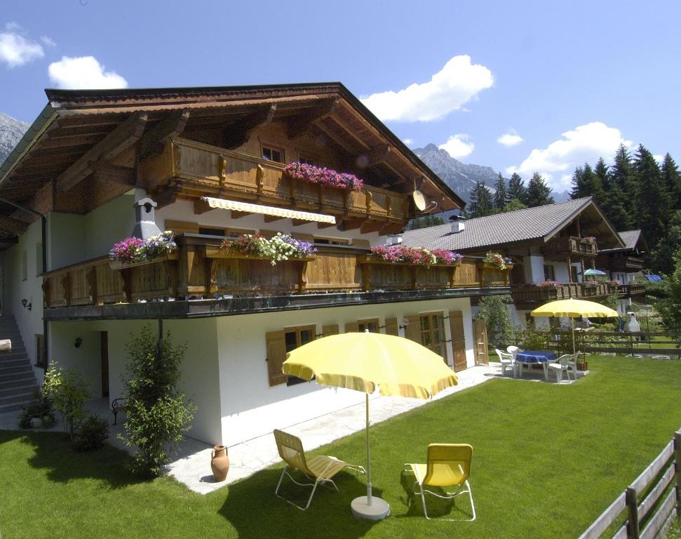 a house with an umbrella and chairs in a yard at Ferienwohnung Waldblick in Scheffau am Wilden Kaiser