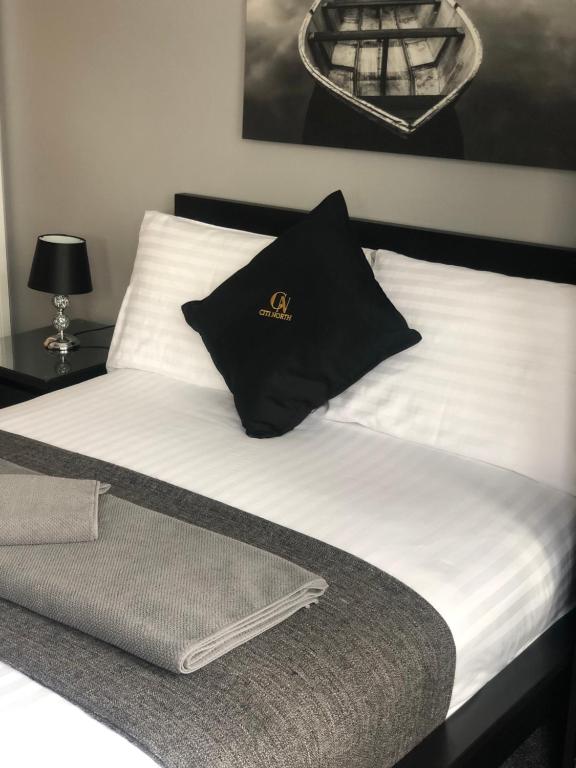 a bed with a black and white pillow on it at Citi North in Belfast