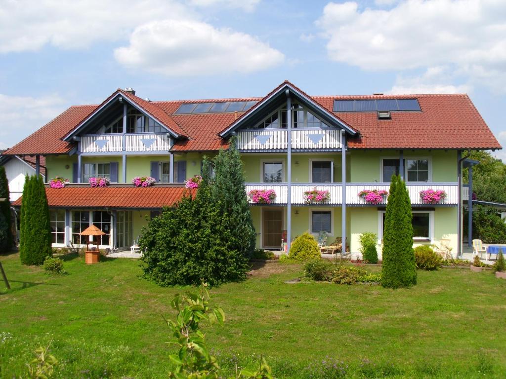 une grande maison avec un toit rouge dans l'établissement Landhaus Brummer, à Bad Birnbach
