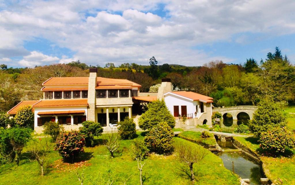 uma grande casa com um jardim e uma ponte em Finca Briabí em La Cañiza