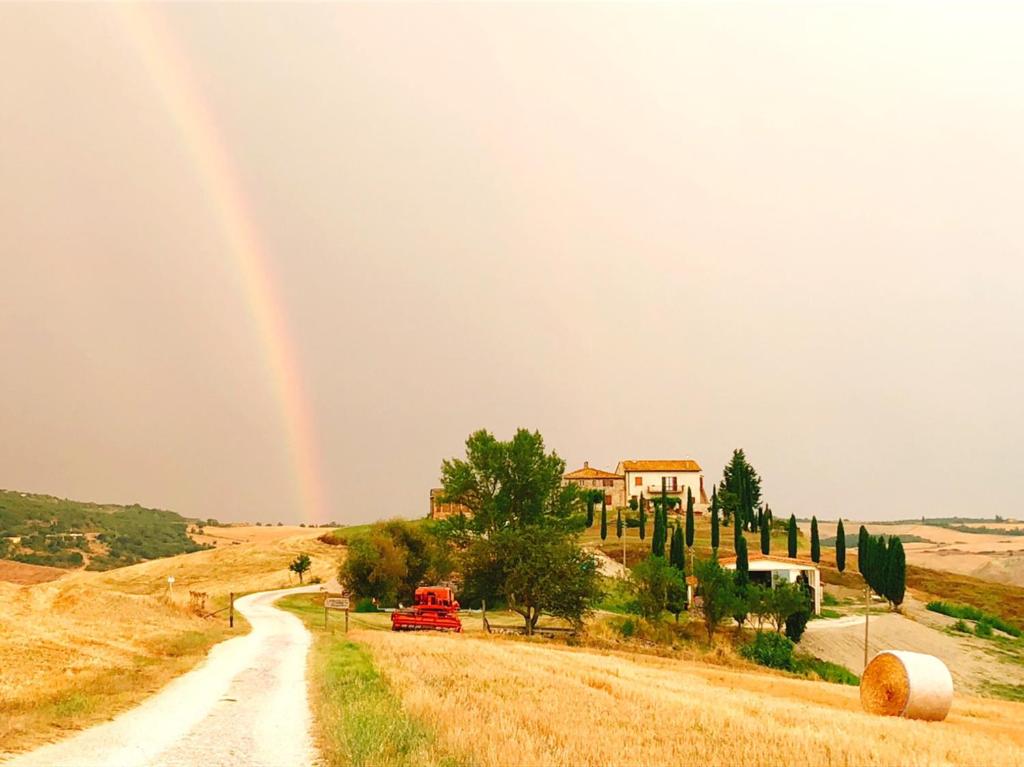a rainbow in the sky over a road with a red car at Podere Poggio Salto in Pienza