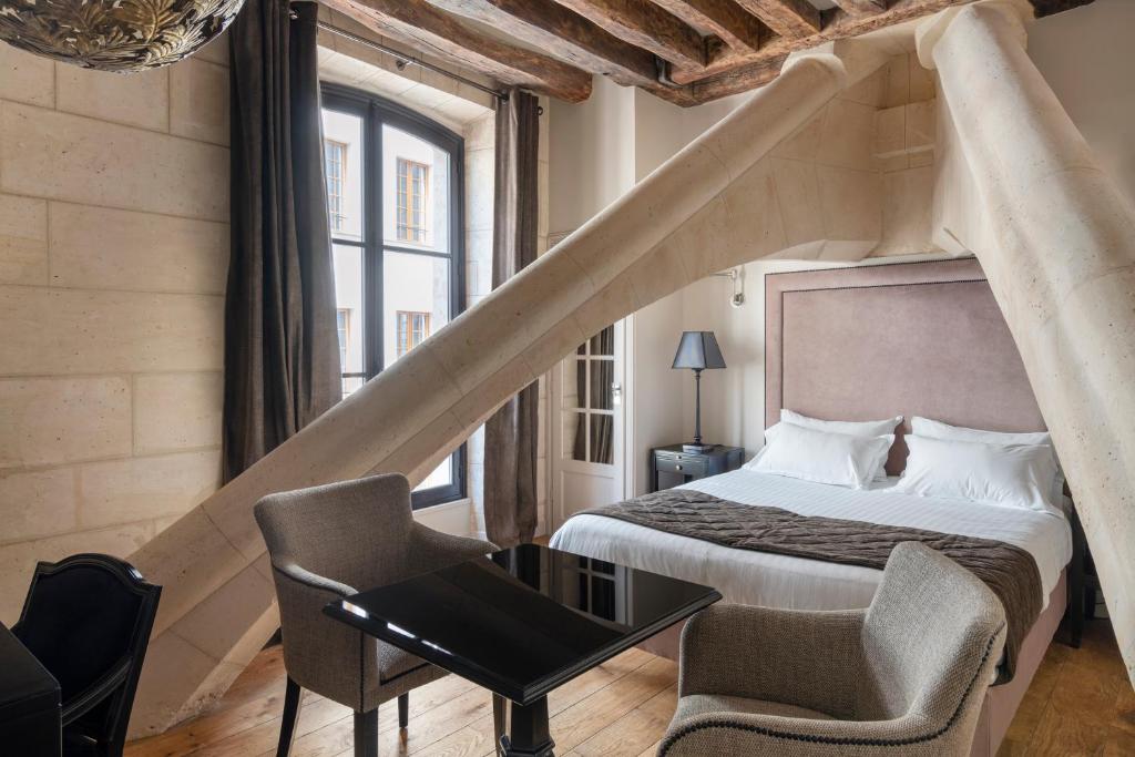 um quarto com uma cama, uma mesa e uma cadeira em Hôtel Le Presbytère em Paris