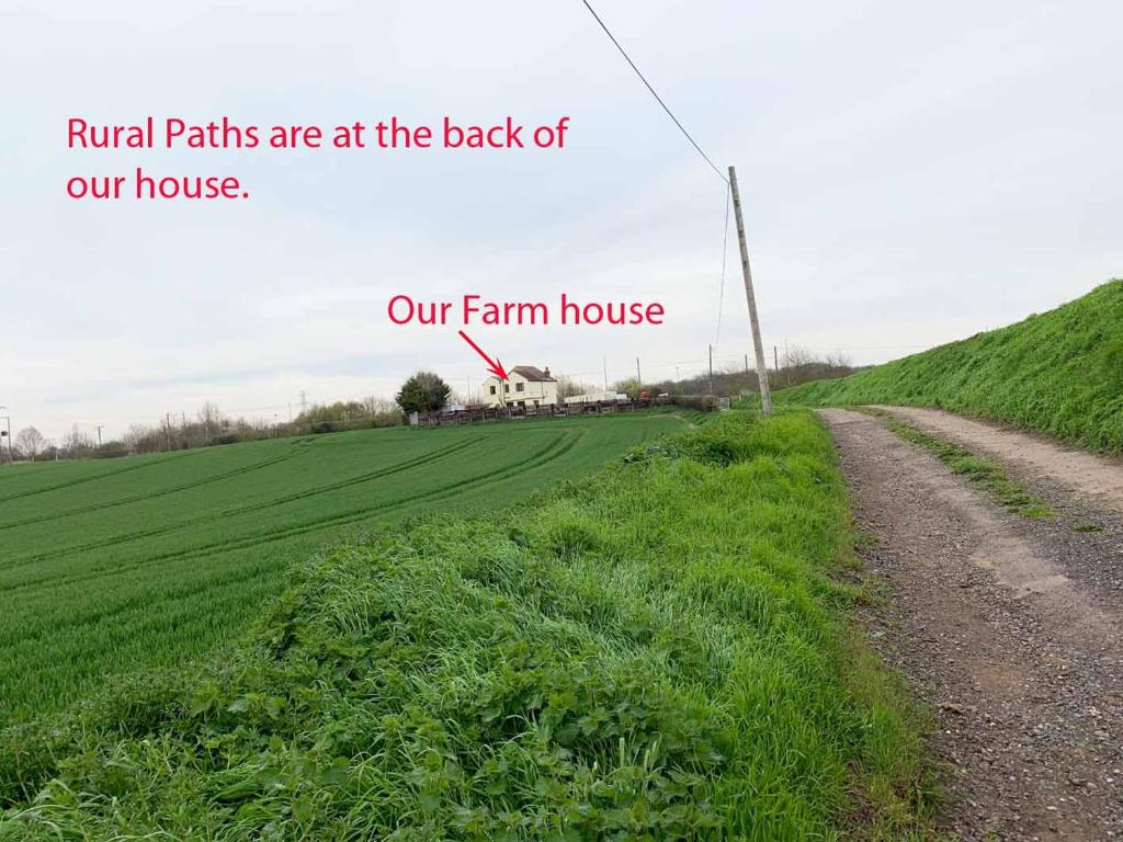 a field with a farm house and a dirt road at Bean Farm House Apartment in Stonewood