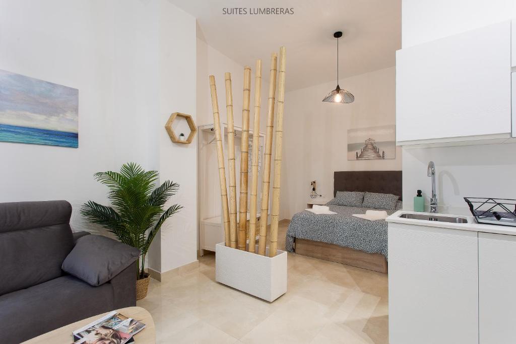 a living room with a bed and a kitchen at Suites Lumbreras in Seville