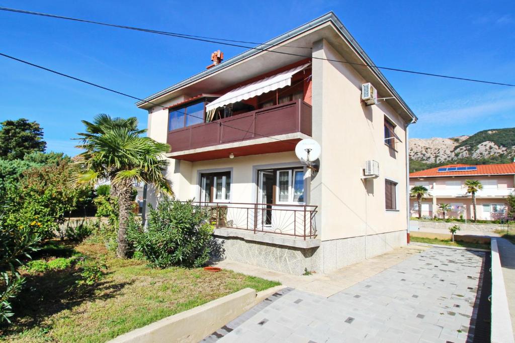 a house with a balcony and a palm tree at Apartment Mihaela in Baška