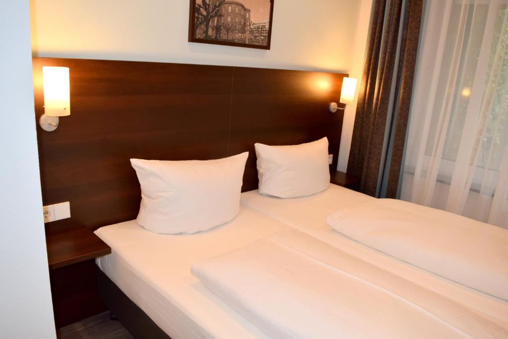 a hotel room with a bed with white sheets and pillows at Trip Inn Budget Hotel Messe in Frankfurt/Main