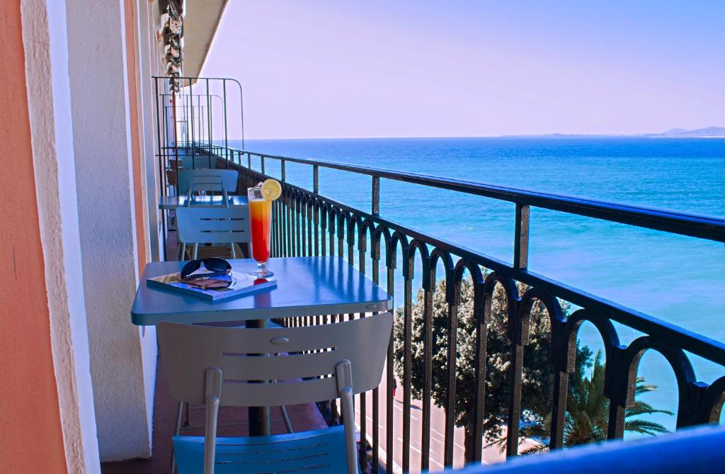 a balcony with a table and chairs and the ocean at Hotel Suisse in Nice