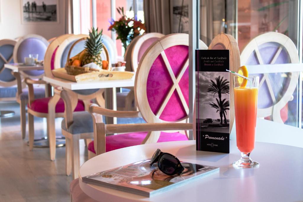 a table with a glass of orange juice and a drink at Hotel Suisse in Nice