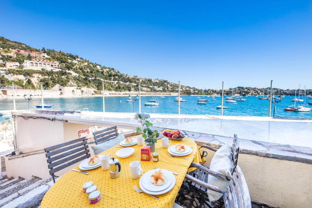 une table jaune avec des chaises et une vue sur le port dans l'établissement Quai des Marinières AP2015 by Riviera Holiday Homes, à Villefranche-sur-Mer