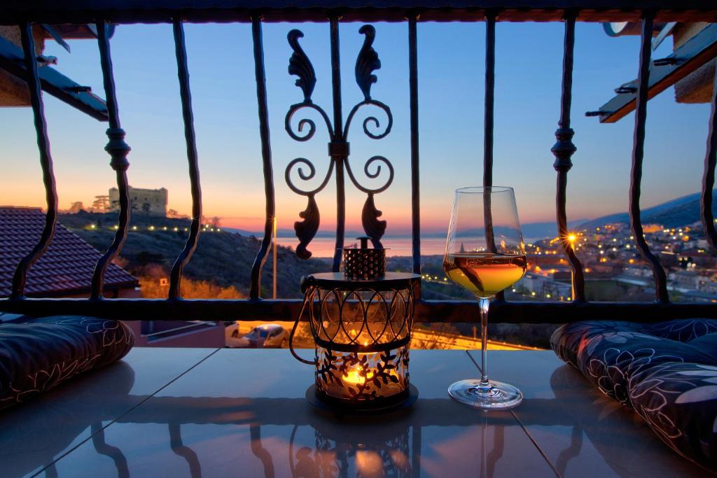a glass of wine on a table in front of a window at Apartments Prpic in Senj