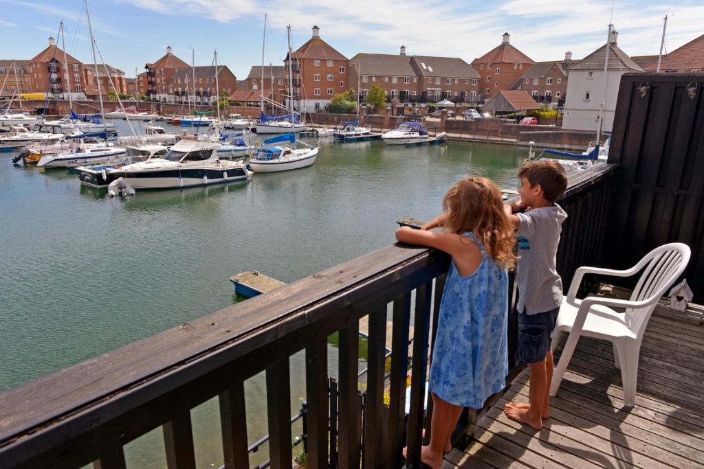 a boy and a girl standing on a deck looking at boats at Sail Away in Eastbourne