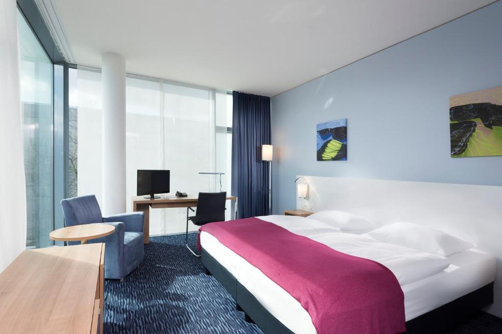 ベルリンにあるSeminaris CampusHotel Berlinの大きなベッドとデスクが備わるホテルルームです。