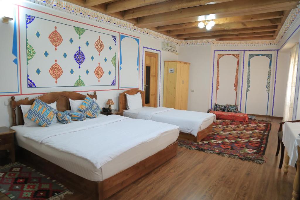 a bedroom with two beds and a painting on the wall at As-Salam Boutique Hotel in Bukhara