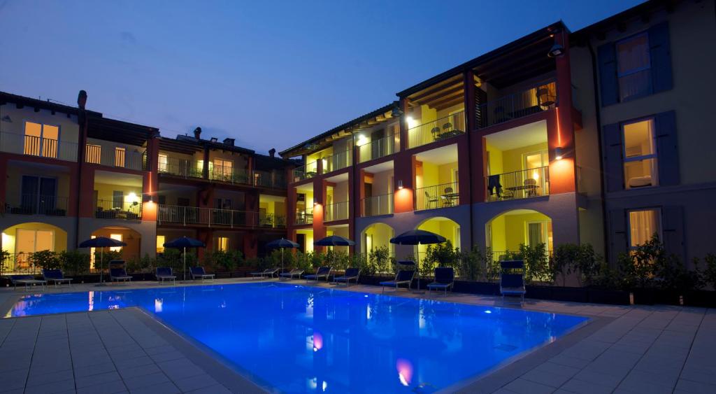 una piscina di fronte a un edificio di notte di Residence Maroadi a Torbole