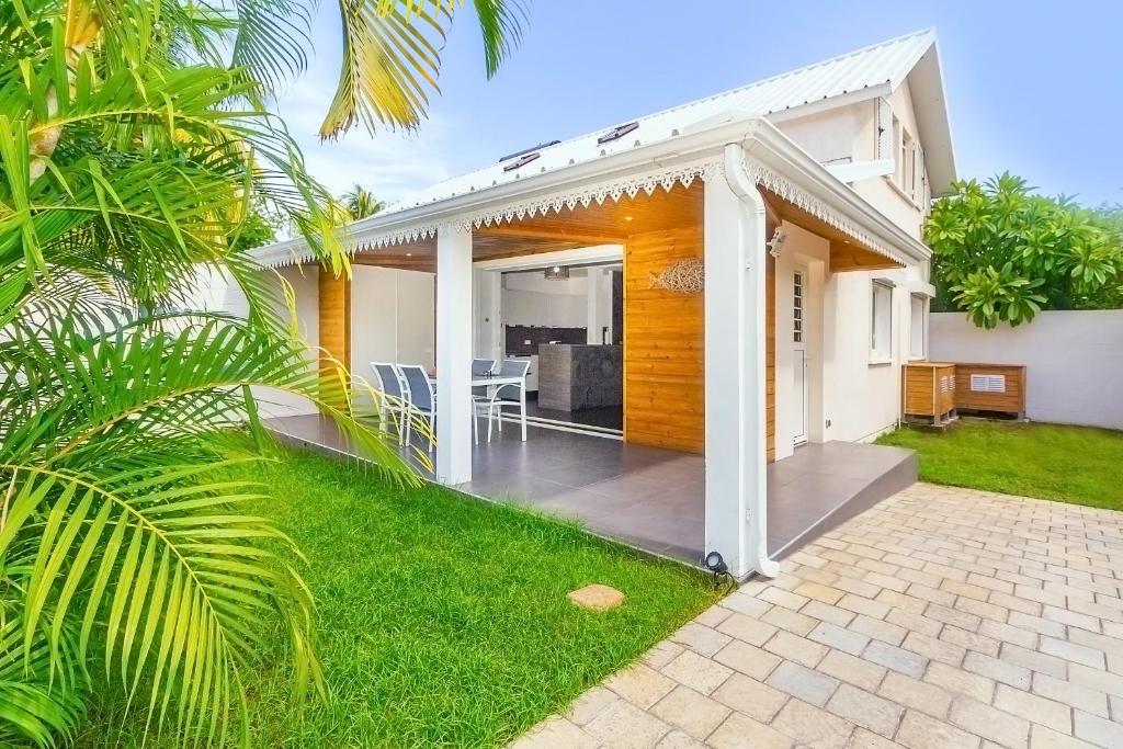 a white house with a patio with a table at Lagoon ! Jolie villa à 2 pas du lagon de la Saline in La Saline les Bains