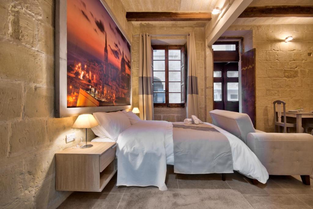 a bedroom with a large white bed and a table at Laparelli Suites: Luxury Suite 2 in Valletta