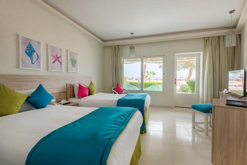 Habitación de hotel con 2 camas y TV en Shams Lodge en Hurghada