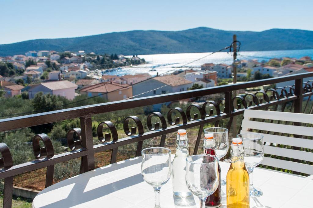una mesa con botellas de vino y copas en el balcón en Apartments Jozic, en Seget Vranjica