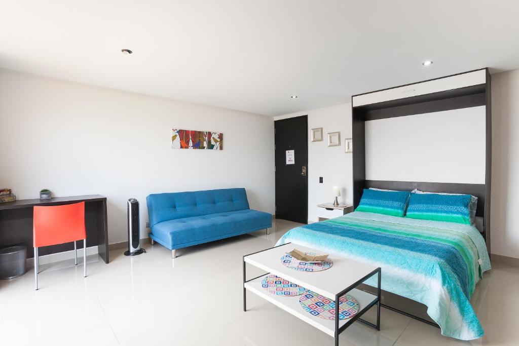 1 dormitorio con 1 cama azul y 1 sofá azul en Apartamento Poblado Frontera, en Medellín