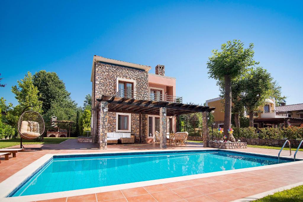 a swimming pool in front of a house at Olympus Villas in Paralía Skotínis