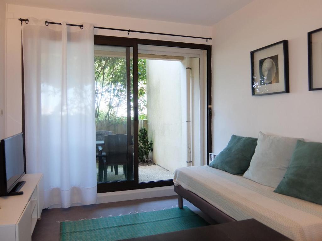 un salon avec un canapé et une porte coulissante en verre dans l'établissement La Marina avec Parking et accès Piscine, à La Rochelle
