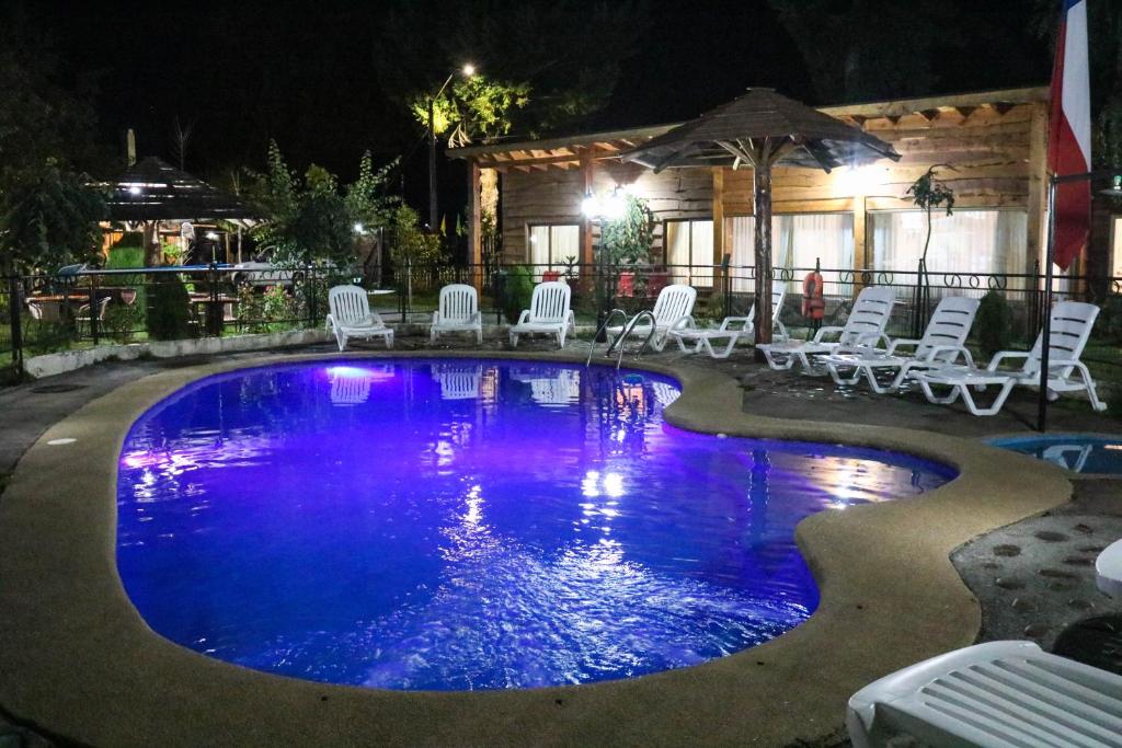 a large swimming pool with chairs and a house at Cabañas Los Tilos in Malalcahuello