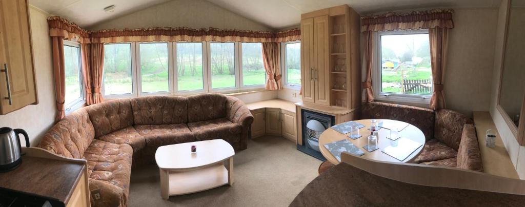a living room with a couch and a table at Yeovil Accomodation Business & Pleasure, 2 dble Bedrooms, Bathroom en-suite, Kitchen, Lounge, Diner, Garden, 365 acres Forest & Streams, Workers huts available with lrge Van parking in Montacute