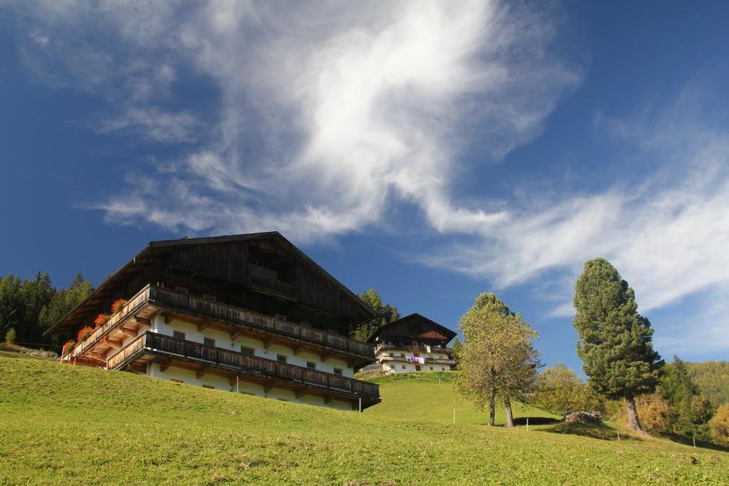 ein Gebäude auf einem grasbewachsenen Hügel mit einem Himmel in der Unterkunft Rasterhof in Sillian