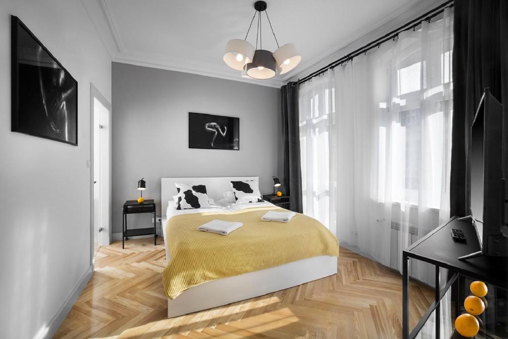 a bedroom with a large bed with a yellow blanket at Apartamenty Pomarańczarnia in Poznań