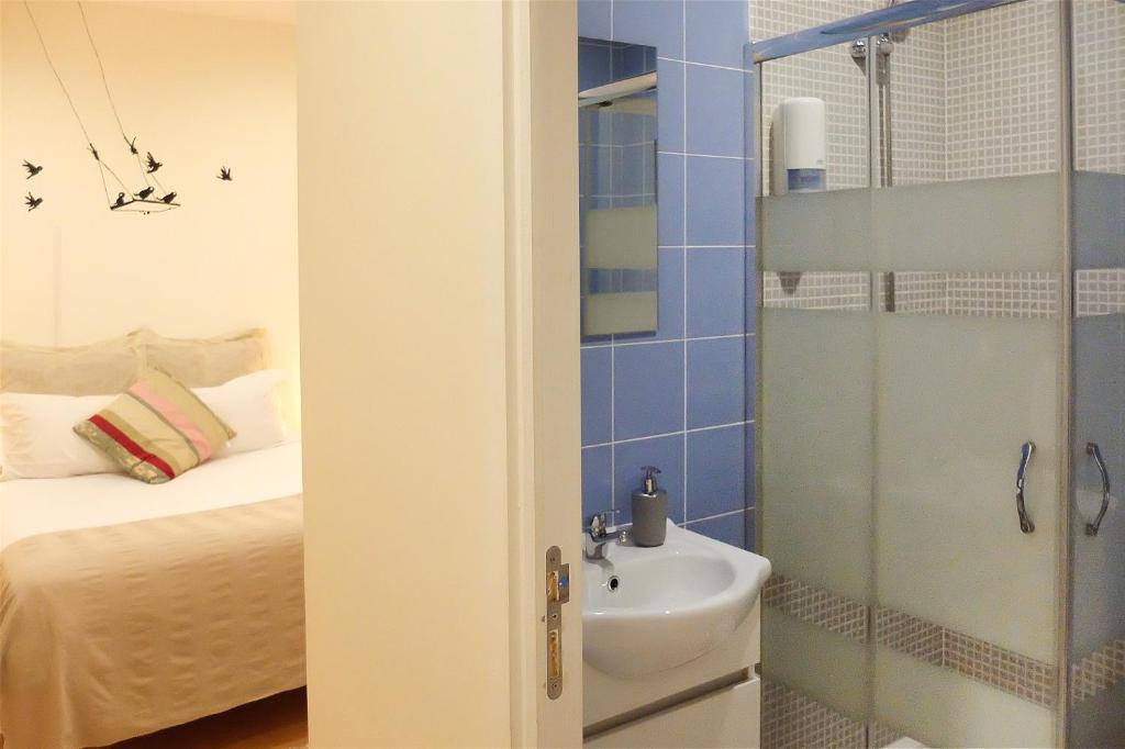 uma casa de banho com um chuveiro, um lavatório e uma cama em Family House em Aveiro