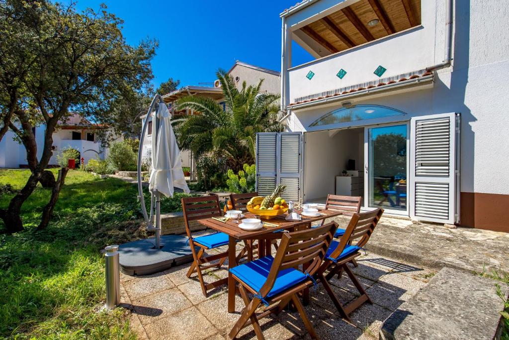 eine Terrasse mit einem Tisch, Stühlen und einem Sonnenschirm in der Unterkunft Apartments in pinewood near the sea in Mali Lošinj