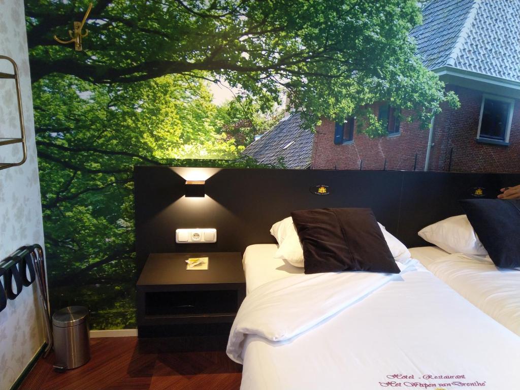 two beds in a room with a large window at Hotel Het Wapen van Drenthe in Roden