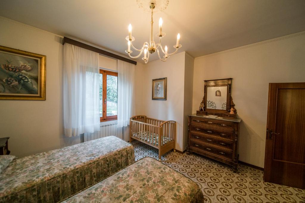 ein Schlafzimmer mit 2 Betten, einem Kinderbett und einem Kronleuchter in der Unterkunft VILLA IL TRUFOLO in Pratolino