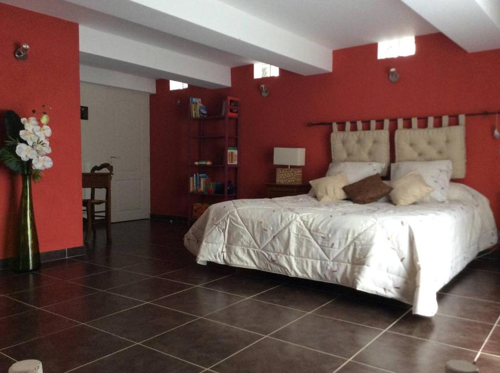 a bedroom with a white bed with a red wall at Clôt de Félines Chambre spacieuse in Entrevaux