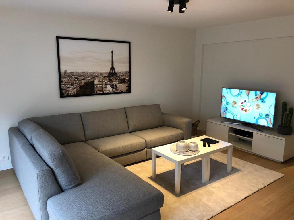 een woonkamer met een bank en een tv bij Ocean Breeze in Oostende