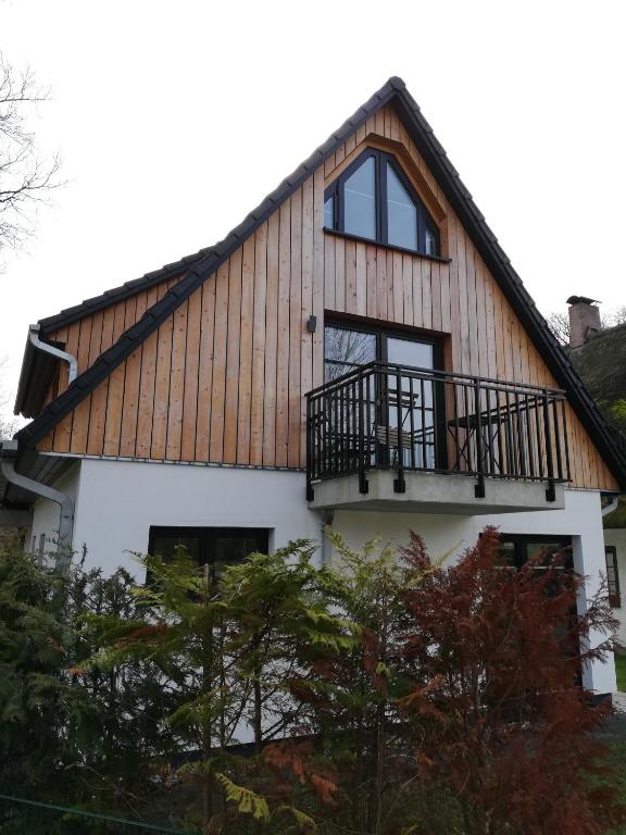 a house with a gambrel roof and a balcony at Darßer Strandgut - Haus Ahrenshooper Holz in Ahrenshoop