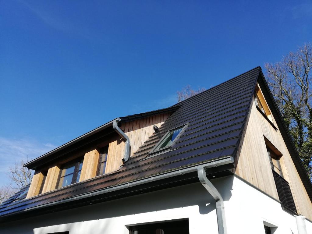 a house with a black roof on top of it at Darßer Strandgut - Haus Ahrenshooper Holz in Ahrenshoop