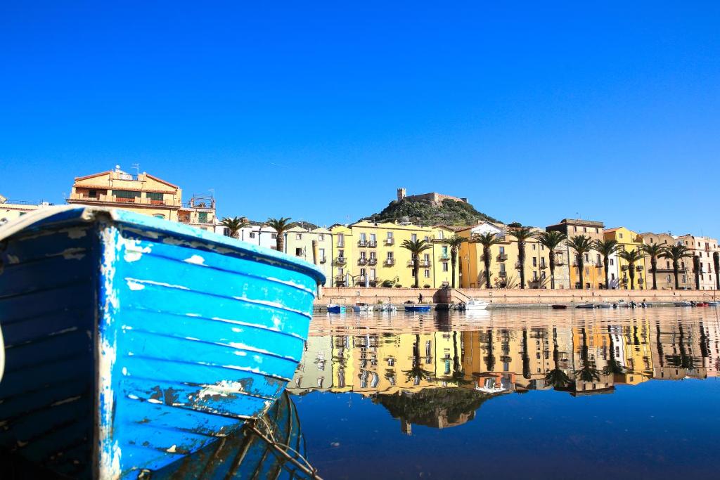 Una barca blu seduta in acqua di fronte a una città di Corte Fiorita Albergo Diffuso a Bosa