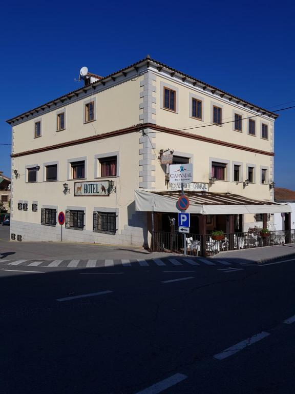 un grand bâtiment blanc au coin d'une rue dans l'établissement Hotel Carvajal, à Torrejón el Rubio