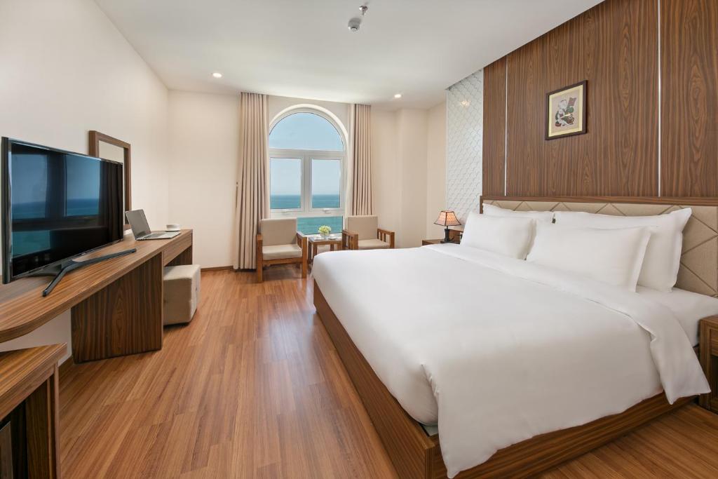 a bedroom with a large white bed and a television at De Lamour Hotel in Da Nang