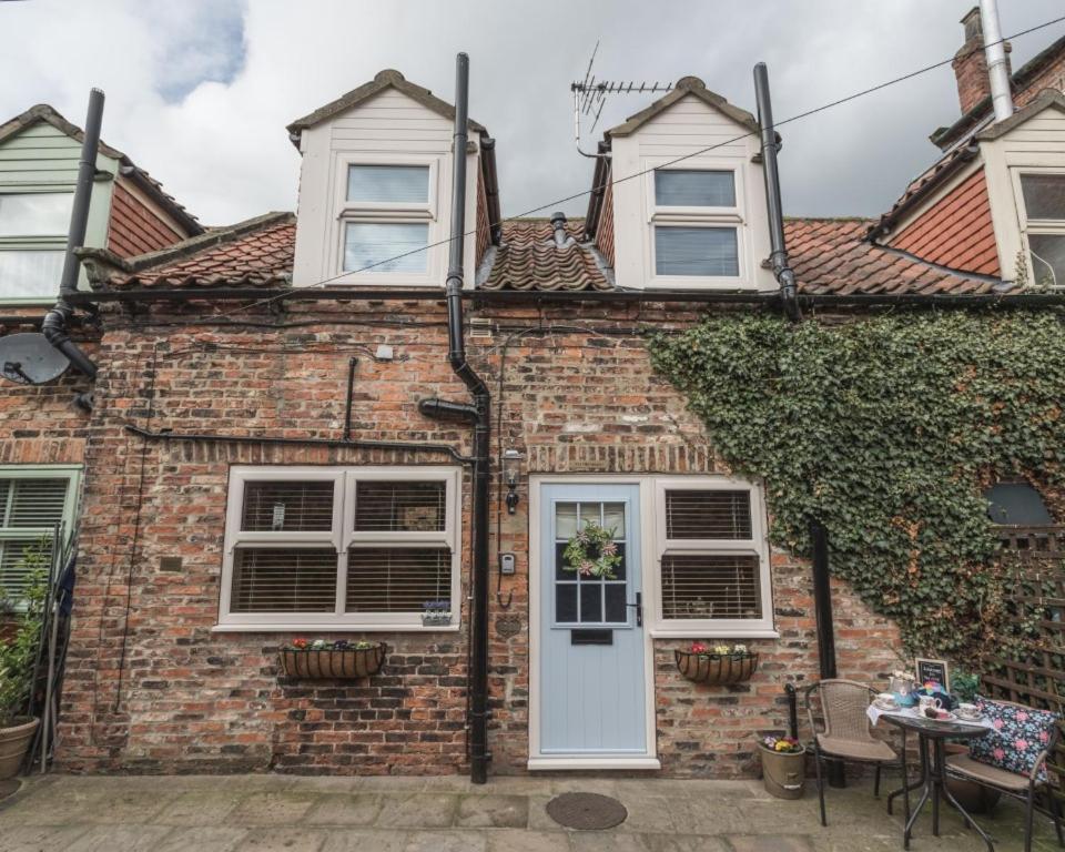 a brick house with a white door and a table at The Old Surgery in Thirsk