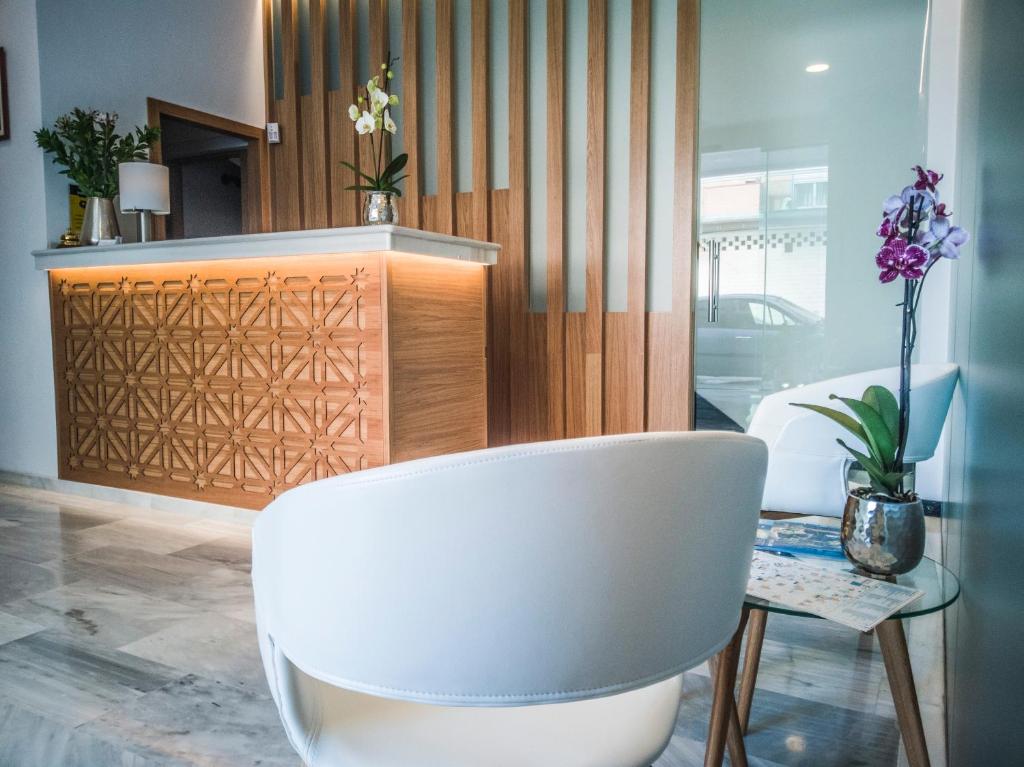 una silla blanca en una habitación con mesa en Hotel Abadi en Córdoba